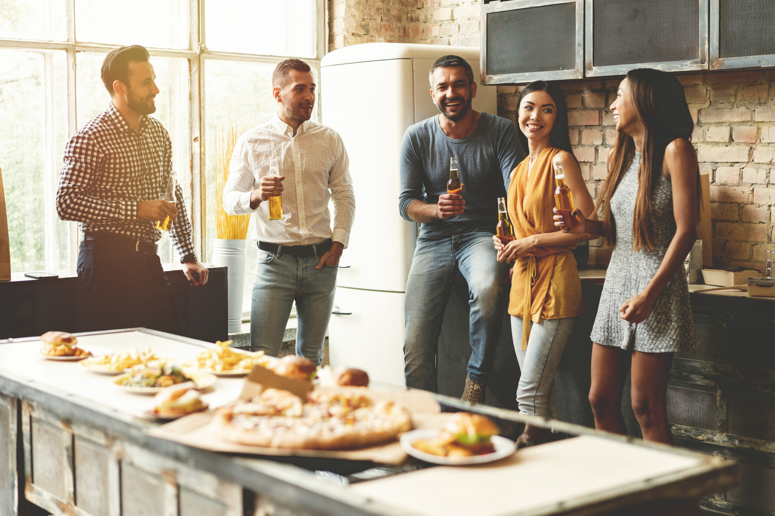Group of people enjoying food and drinks in kitchen