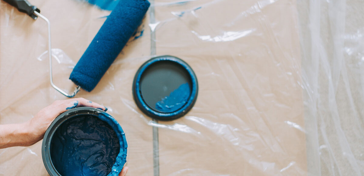 A bucket of blue paint and a paint brush