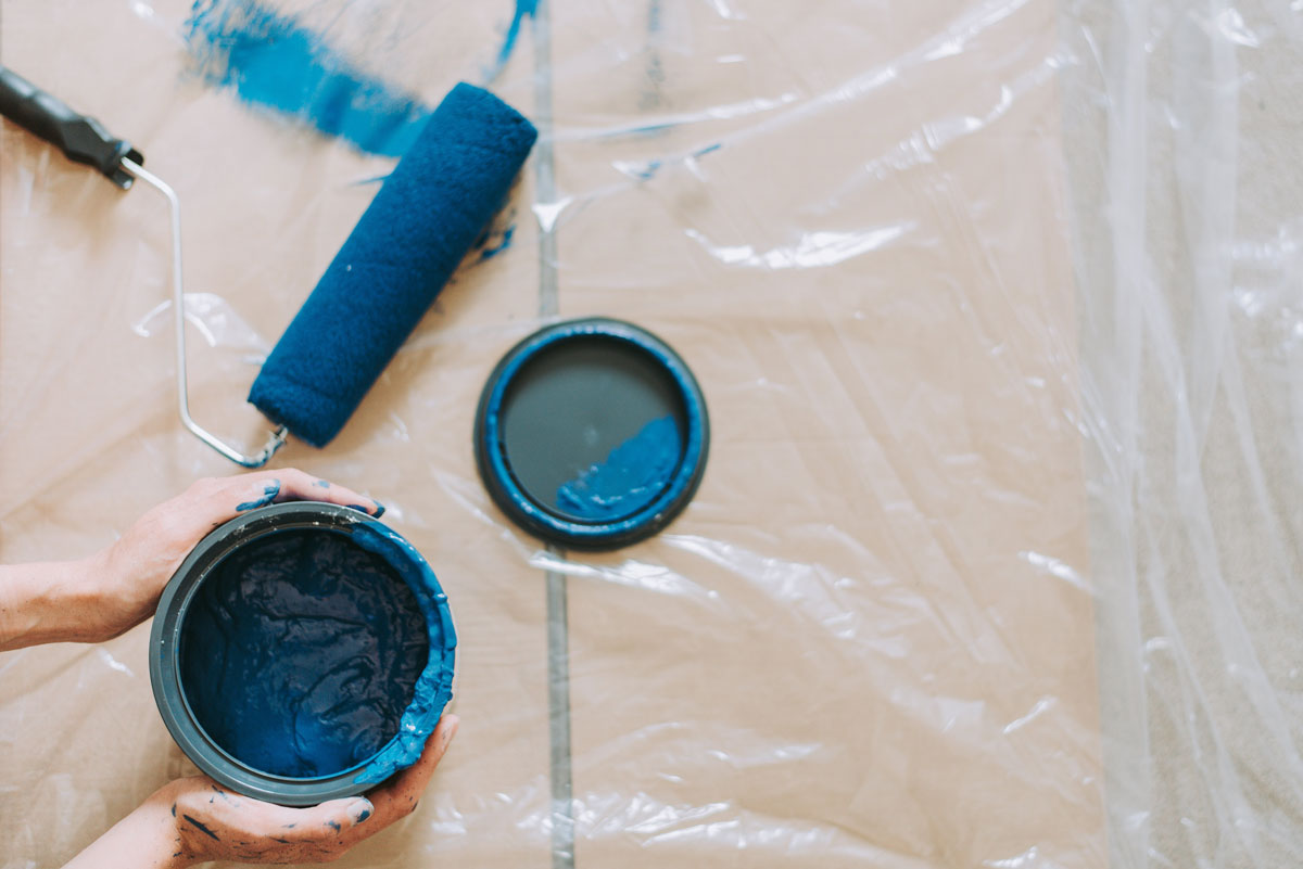 A bucket of blue paint and a paint brush
